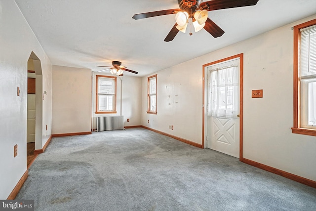 unfurnished room featuring carpet, radiator, and ceiling fan