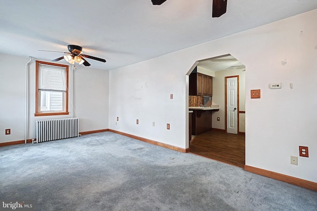 unfurnished room with carpet, ceiling fan, and radiator