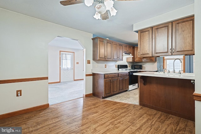 kitchen with white gas range, ceiling fan, light hardwood / wood-style floors, and a wealth of natural light