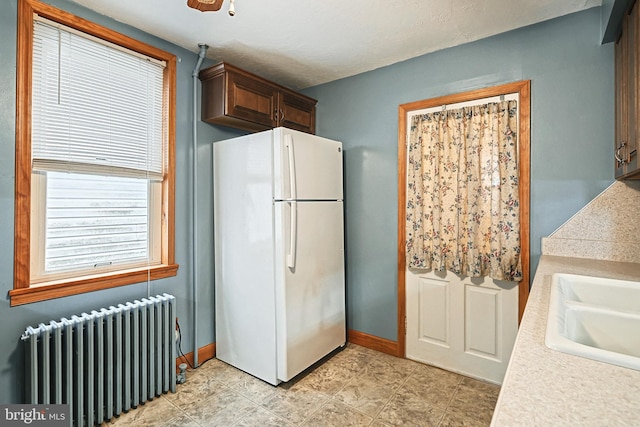 kitchen featuring ceiling fan, white fridge, radiator heating unit, and sink