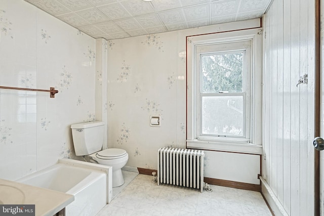 bathroom with a bathing tub, vanity, toilet, and radiator