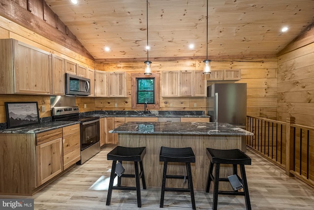 kitchen with light hardwood / wood-style floors, appliances with stainless steel finishes, a center island, decorative light fixtures, and sink