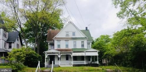 back of property with a lawn and covered porch