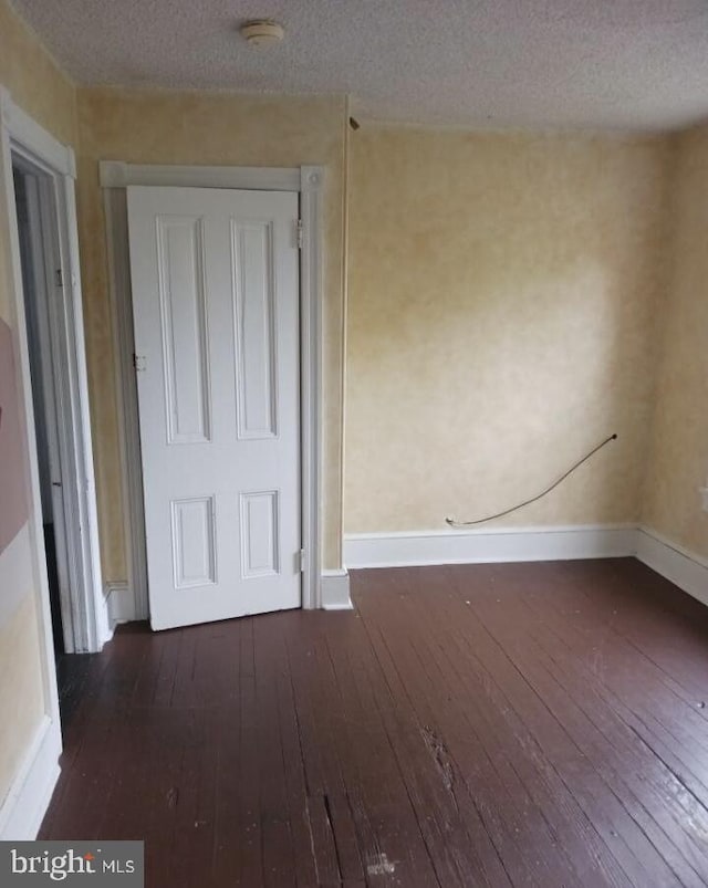 unfurnished room with dark hardwood / wood-style floors and a textured ceiling