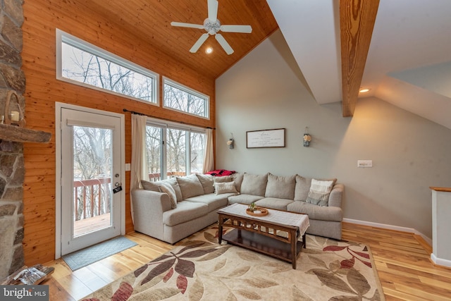 living room featuring ceiling fan, wood walls, light hardwood / wood-style floors, and high vaulted ceiling