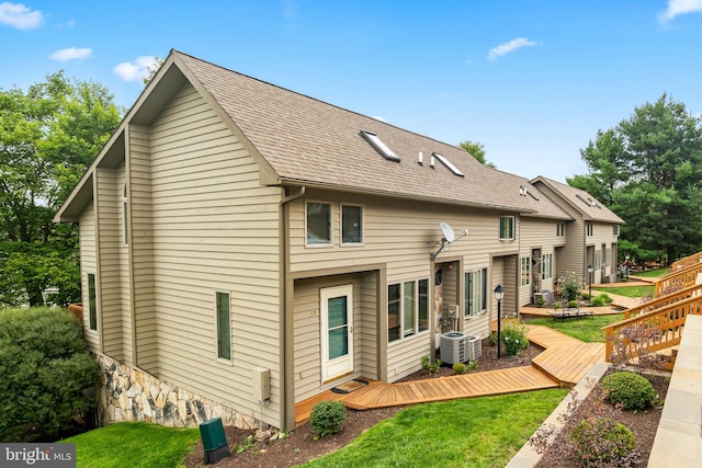 rear view of house featuring ac unit, a deck, and a lawn