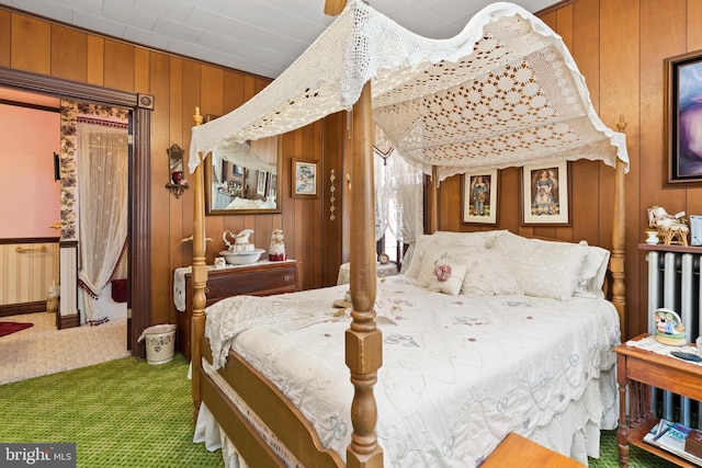 bedroom featuring carpet flooring, wooden walls, and radiator heating unit