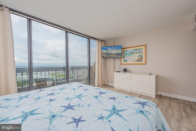 bedroom featuring access to exterior, light hardwood / wood-style flooring, floor to ceiling windows, and multiple windows