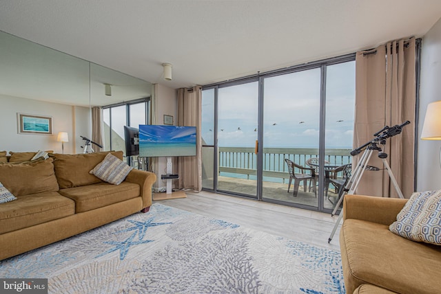 living room with hardwood / wood-style floors, a water view, and expansive windows