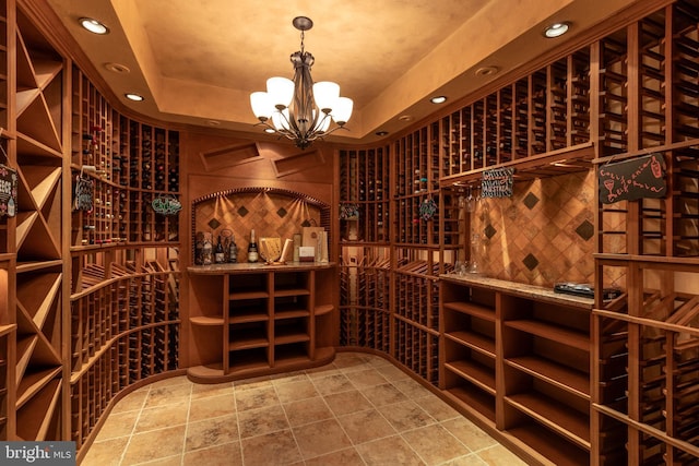 wine room with a raised ceiling and a notable chandelier