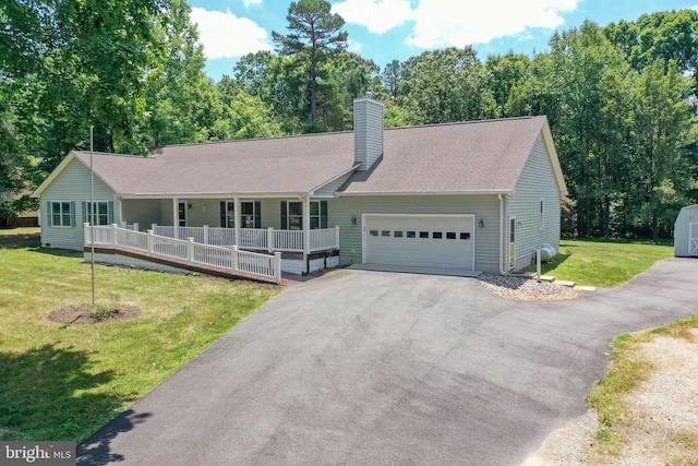 view of front of home featuring covered porch, a garage, and a front lawn