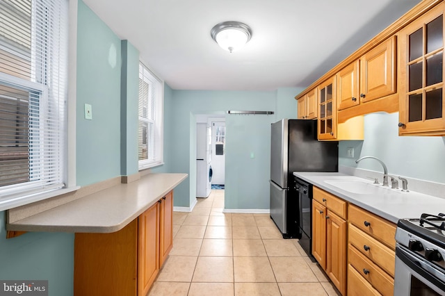 kitchen featuring dishwasher, sink, stainless steel stove, and light tile patterned floors