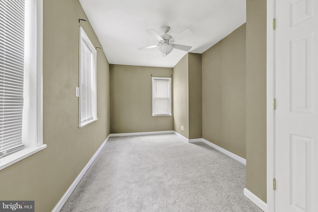 spare room featuring a wealth of natural light, ceiling fan, and light colored carpet