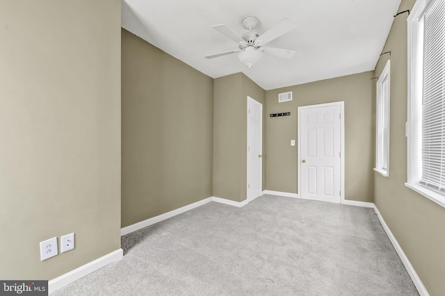 empty room with ceiling fan and light carpet