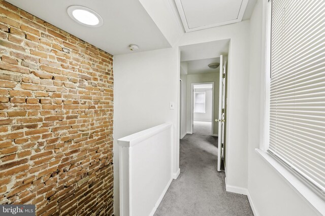 corridor with light carpet and brick wall