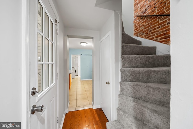 staircase featuring hardwood / wood-style floors and brick wall