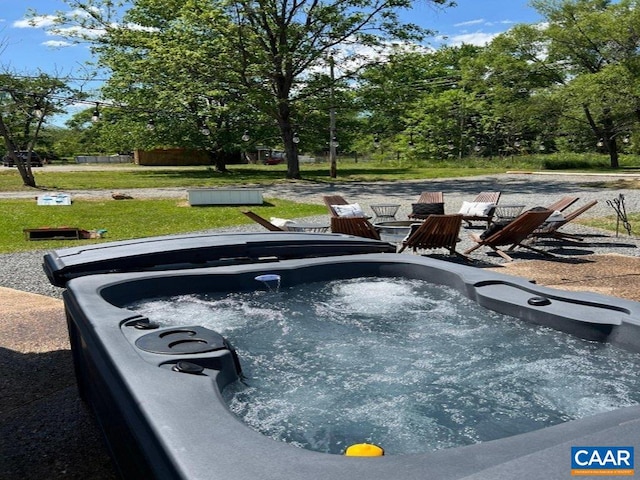 view of pool with a hot tub and a lawn