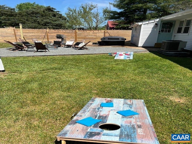 view of yard featuring a fire pit, central AC unit, a patio, a hot tub, and a storage unit