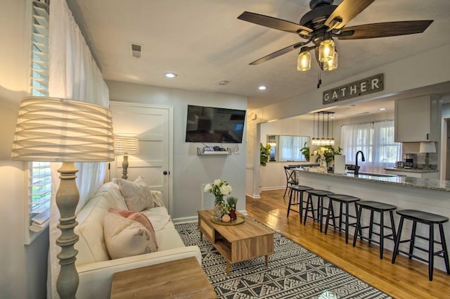 living room with ceiling fan, light wood-type flooring, a wealth of natural light, and sink