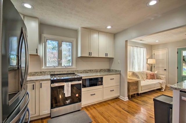 kitchen with light stone counters, white cabinets, and stainless steel appliances