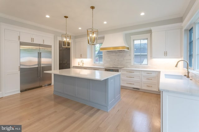 kitchen with custom exhaust hood, a center island, stainless steel built in fridge, and white cabinetry