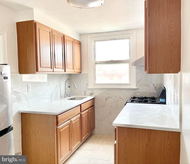 kitchen featuring sink, backsplash, stainless steel fridge, light tile patterned floors, and stove