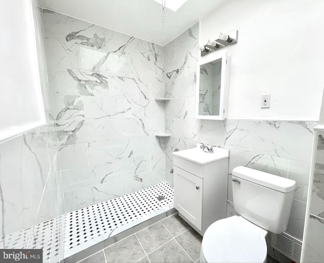 bathroom with tile patterned flooring, vanity, a shower, tile walls, and toilet