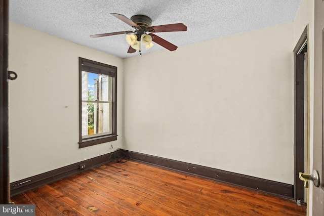 empty room featuring ceiling fan, a textured ceiling, and dark wood-type flooring