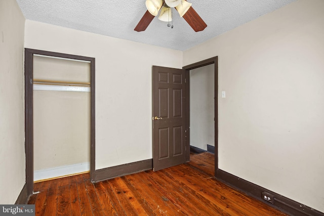 unfurnished bedroom featuring ceiling fan, a closet, dark hardwood / wood-style floors, and a textured ceiling