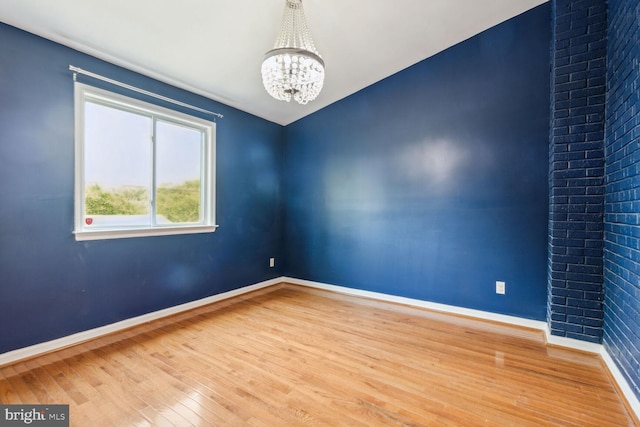 unfurnished room with a chandelier and hardwood / wood-style flooring