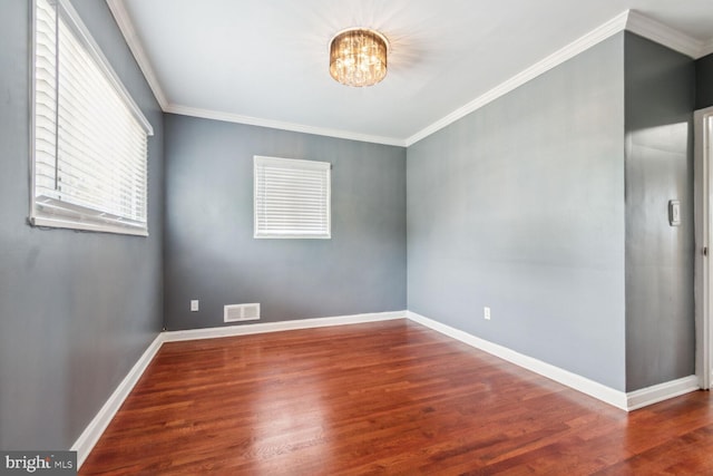 spare room featuring an inviting chandelier, dark wood-type flooring, and crown molding