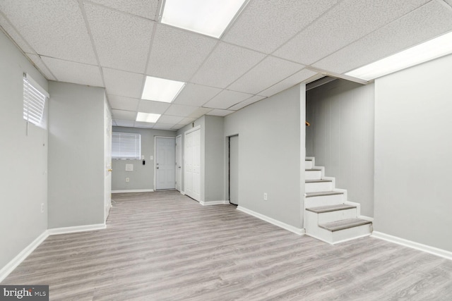 basement with a drop ceiling and light hardwood / wood-style flooring