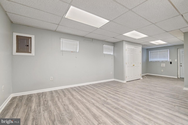 basement featuring electric panel and light hardwood / wood-style flooring