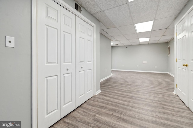 basement with a drop ceiling and light hardwood / wood-style floors