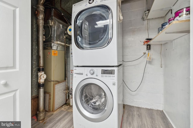 clothes washing area featuring stacked washer / dryer and light hardwood / wood-style flooring