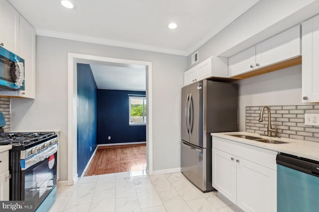 kitchen with appliances with stainless steel finishes, white cabinetry, crown molding, and sink