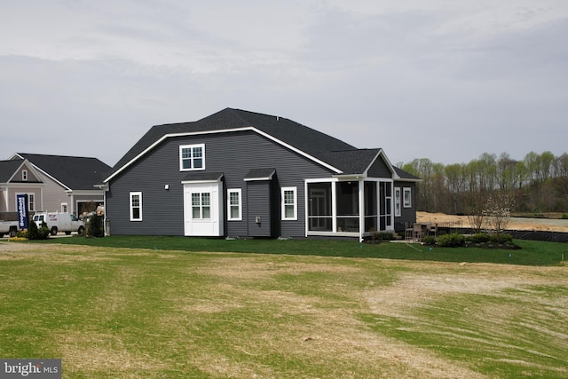 back of house featuring a sunroom and a lawn