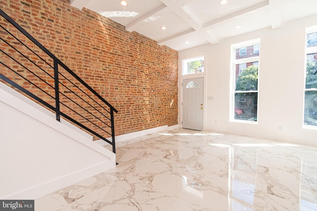 foyer with beam ceiling, brick wall, and coffered ceiling