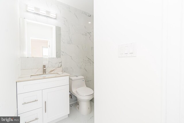 bathroom featuring vanity, tile walls, and toilet