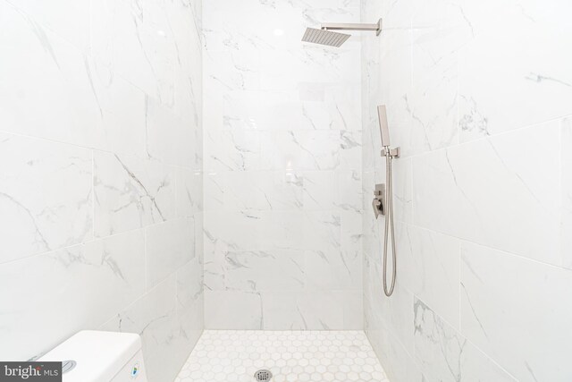 bathroom featuring tiled shower and toilet