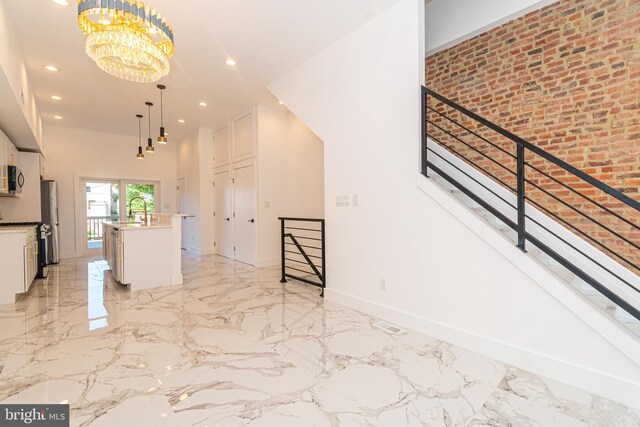 kitchen featuring a kitchen island with sink, sink, hanging light fixtures, a notable chandelier, and white cabinetry