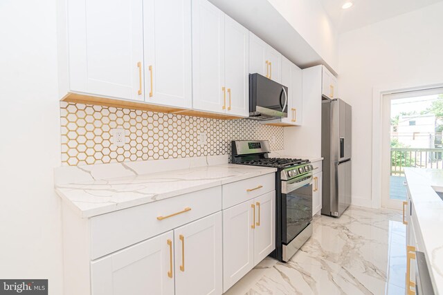 kitchen with tasteful backsplash, white cabinetry, light stone countertops, and appliances with stainless steel finishes