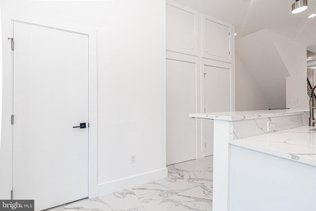 interior space featuring white cabinets, kitchen peninsula, and light stone countertops