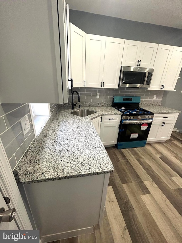 kitchen featuring appliances with stainless steel finishes, white cabinetry, dark wood-type flooring, tasteful backsplash, and sink