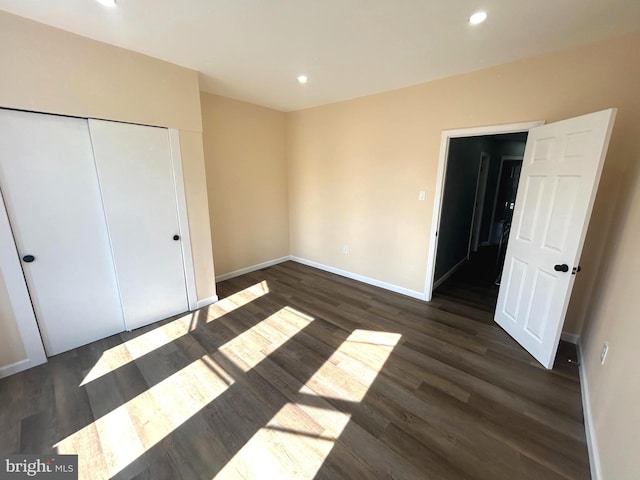 unfurnished bedroom with a closet and dark wood-type flooring