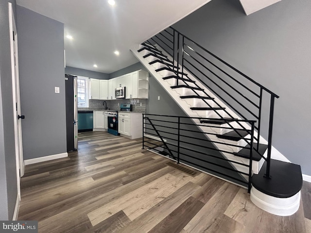 staircase with wood-type flooring and sink