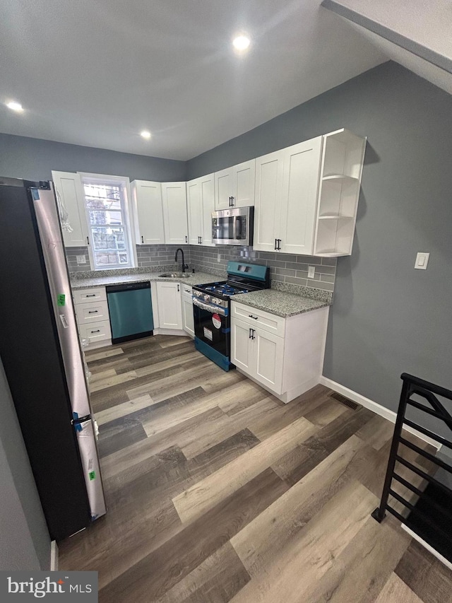 kitchen with white cabinetry, sink, stainless steel appliances, and hardwood / wood-style flooring