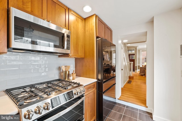 kitchen with decorative backsplash, dark tile patterned floors, and appliances with stainless steel finishes