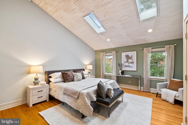 bedroom with multiple windows, lofted ceiling with skylight, and light hardwood / wood-style flooring