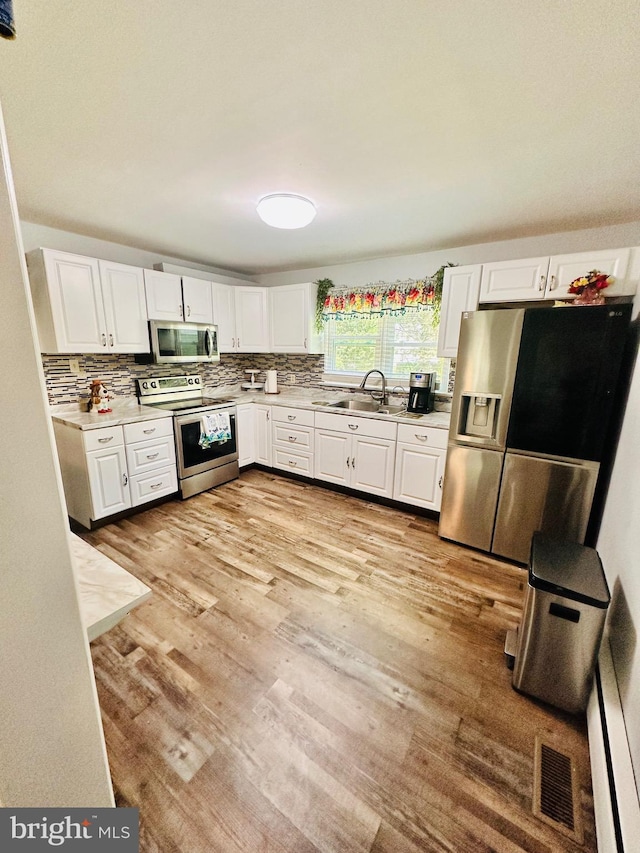 kitchen with white cabinets, light hardwood / wood-style floors, sink, and appliances with stainless steel finishes